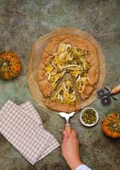 Wall Mural - Savory gluten free galette with pumpkin, brie cheese and pumpkin seeds on buckwheat crust on green concrete background. Gluten free recipes. Pumpkin baking.