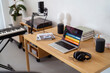 © Studio Marmellata - A sleek, modern desk with a laptop displaying audio editing software, a microphone, headphones, and a keyboard creates a dedicated workspace in a home with a minimalist aesthetic and practical decor.
