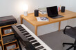 © Studio Marmellata - A sleek home studio desk featuring a laptop, a keyboard, speakers, and books, creating a modern and minimalist workspace ideal for productivity in a relaxed indoor environment.