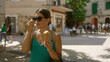 © Krakenimages.com - Young woman enjoying ice cream outdoors in valldemossa, mallorca, spain, wearing sunglasses and a green dress on a sunny day in a picturesque town square