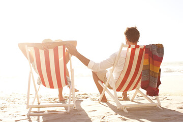 Beach, couple and relax on chair for break, support and bonding with love in Mauritius. Back, people and relationship on lounger on summer holiday, honeymoon and adventure for care, trust and rest