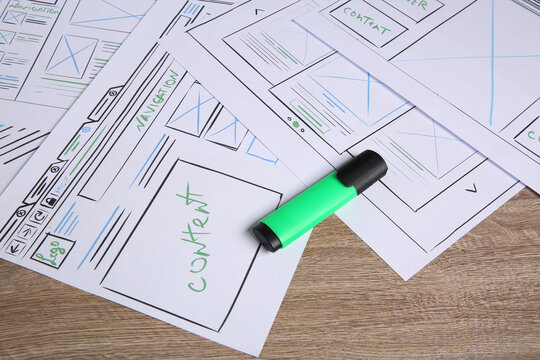 Developing UI design. Sketches of website wireframes and felt pen on wooden table, closeup