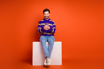 Aufkleber - Full size photo of nice young male sit white cube hold device wear trendy striped violet outfit isolated on orange color background