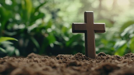 A wooden cross is placed in the dirt, surrounded by green plants. Concept of spirituality and reverence, as the cross is a symbol of faith and hope