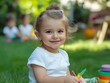 © VISUAL BACKGROUND - A little girl sitting on the grass with colored pencils