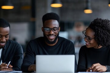 Poster - A group of three people collaborates happily in a modern office setting, focused on a laptop, symbolizing teamwork and professional camaraderie.