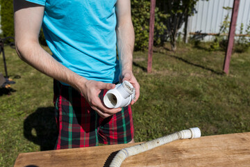 A man is holding a white pipe on a table