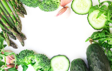 Wall Mural - Frame of green vegetables broccoli, arugula, cucumber, asparagus and garlic on white background