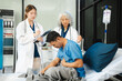 © NINENII - doctor talking to male patient at bed in hospital.