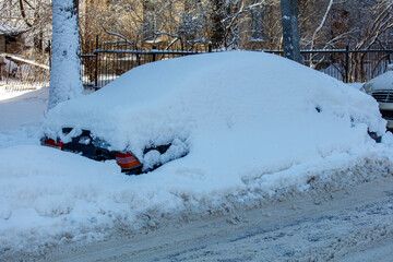 Wall Mural - A car is covered in snow and is parked on a snowy street