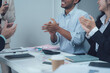 © Kritdanai - Appreciation and Collaboration: A diverse group of business professionals engaged in a lively meeting, applauding and celebrating a shared success.