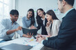 © Kritdanai - Collaborative Business Meeting: A diverse team of smiling business professionals collaborates around a table, reviewing documents and engaging in lively discussion.