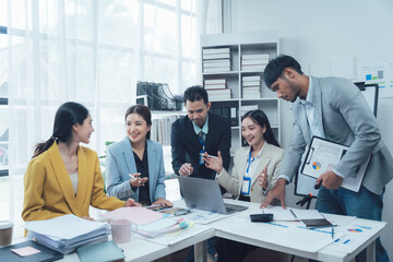 Wall Mural - Business Team Brainstorming:  A diverse group of professionals collaborates around a laptop, analyzing data and strategizing for success in a modern office setting.   