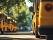 © pornchan - Event parking for school buses, the main yellow bus in focus with other buses slightly blurred, under a sunny, clear sky for a cheerful atmosphere