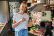 © Geber86 - Young woman filming cooking tutorial in kitchen with fresh vegetables and eggs