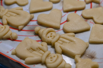 Close-up view of raw Snowman and Christmas tree shaped shortbread (or shortie) holidays cookies lying on baking tray before baking. Soft focus. copy space. Christmas food preparation theme.