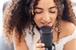 © Studio Marmellata - A close-up of a woman with curly hair and headphones on, as she focuses intently on recording her vocals into a microphone