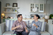 © ultramansk - An elderly couple enjoys a peaceful moment at home, sharing smiles and drinks. The warm and cozy atmosphere emphasizes their deep connection, happiness, and the comfort of spending time together.