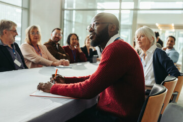 Wall Mural - Confident businessman listening attentively in a meeting with colleagues