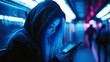 © fotofabrika - A young person with long hair in a hoodie gazes at a phone while sitting in a dimly lit subway car at night