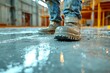 © Outkast - Close-up of a construction worker's boots stepping in wet concrete