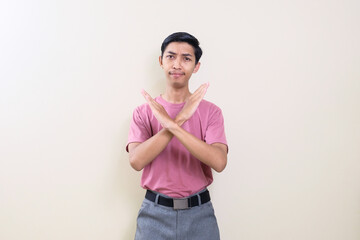 Portrait of young handsome Asian man showing STOP or Rejection expression crossing arms doing negative sign, angry face, isolated background.