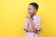 © ArvStd - Happy asian boy standing while looking sideways and pointing something. Isolated on yellow background