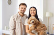 © Studio Romantic - Portrait of a young happy family couple at home, holding dog together. The domestic pet is cherished, and the couple expresses love and joy in their shared moments with beloved animal.