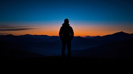 Wall Mural - A solitary figure stands against a breathtaking sunset in a mountainous landscape, perfect for themes of adventure, solitude, or reflection in travel blogs, nature publications