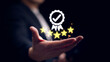 © TimmyTimTim - Businessman hand holding a five star rating with a certificate check mark icon in concept of quality control, service standard feedback review and satisfaction.