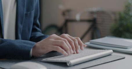 Close-up of male arms in suit typing with wireless keyboard while businessman working with computer in office. Business and technology concept.