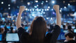© S.JR Stocker - a young Asian woman cheering with her arms raised triumphantly in the air. in a lively conference room with people working on computers