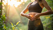 © Unslux - close up of woman hands making heart shape on her stomach yoga pose in the nature, gut health and microbiome