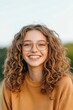 © Mandeep - Portrait of a smiling young woman with curly hair and eyeglasses