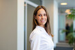 © Minerva Studio - Businesswoman smiling in modern office hallway