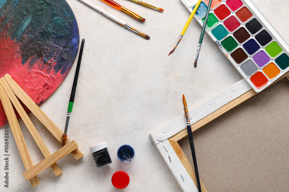 Frame made from artist brushes, paints, canvas and palette on white grunge background