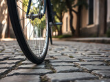 close-up view of a bicycle wheel on cobblestone streets, capturing the charm of a quiet urban pathway in the morning light