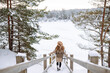 © maxbelchenko - Smiling woman walks near a winter lake. She is enjoying the beautiful winter weather. Nature, travel, winter holidays.
