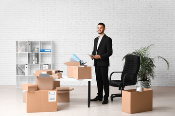 Wall Mural - Young businessman with cardboard boxes in office on moving day