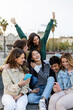 © Xavier Lorenzo - Group of cheerful young friends using smartphones, laughing and having fun together outdoors in a city. Youth community and friendship concept