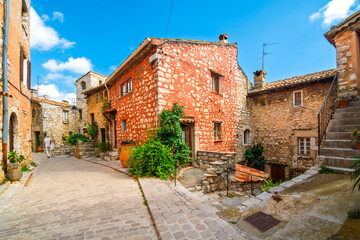 Wall Mural - A couple walks past narrow alleys and winding streets in the medieval stone village of Tourrettes-Sur-Loup, France.