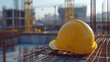 © thien - yellow hard hat rests on steel rebar at construction site, symbolizing safety and progress in building. background features cranes and bustling urban environment