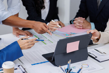 Group of confident business people point to graphs and charts to analyze market data, balance sheet, account, net profit to plan new sales strategies to increase production capacity.	