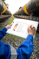 Wall Mural - a worker is checking on chemical hazardous material checklist form with background of train tanker t