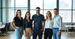 © StockLab - Group of female and male colleagues standing in a bright office in business attire and smiling