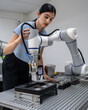 © Nassorn - Hispanic engineer woman working on AI technology in robotics electronics engineering laboratory. University students' research project is programming robot machine with intelligent mechanical control
