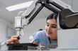 © Nassorn - Hispanic engineer woman working on AI technology in robotics electronics engineering laboratory. University students' research project is programming robot machine with intelligent mechanical control