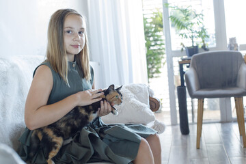 pretty young smiling child girl embracing lovely cat pet at cosy home, lifestyle portrait