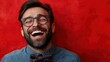 © TYNQ - A man with a beard and glasses laughing with a red background.