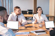 © BullRun - Team of intent coworkers having discussion and using laptop at meeting in conference room